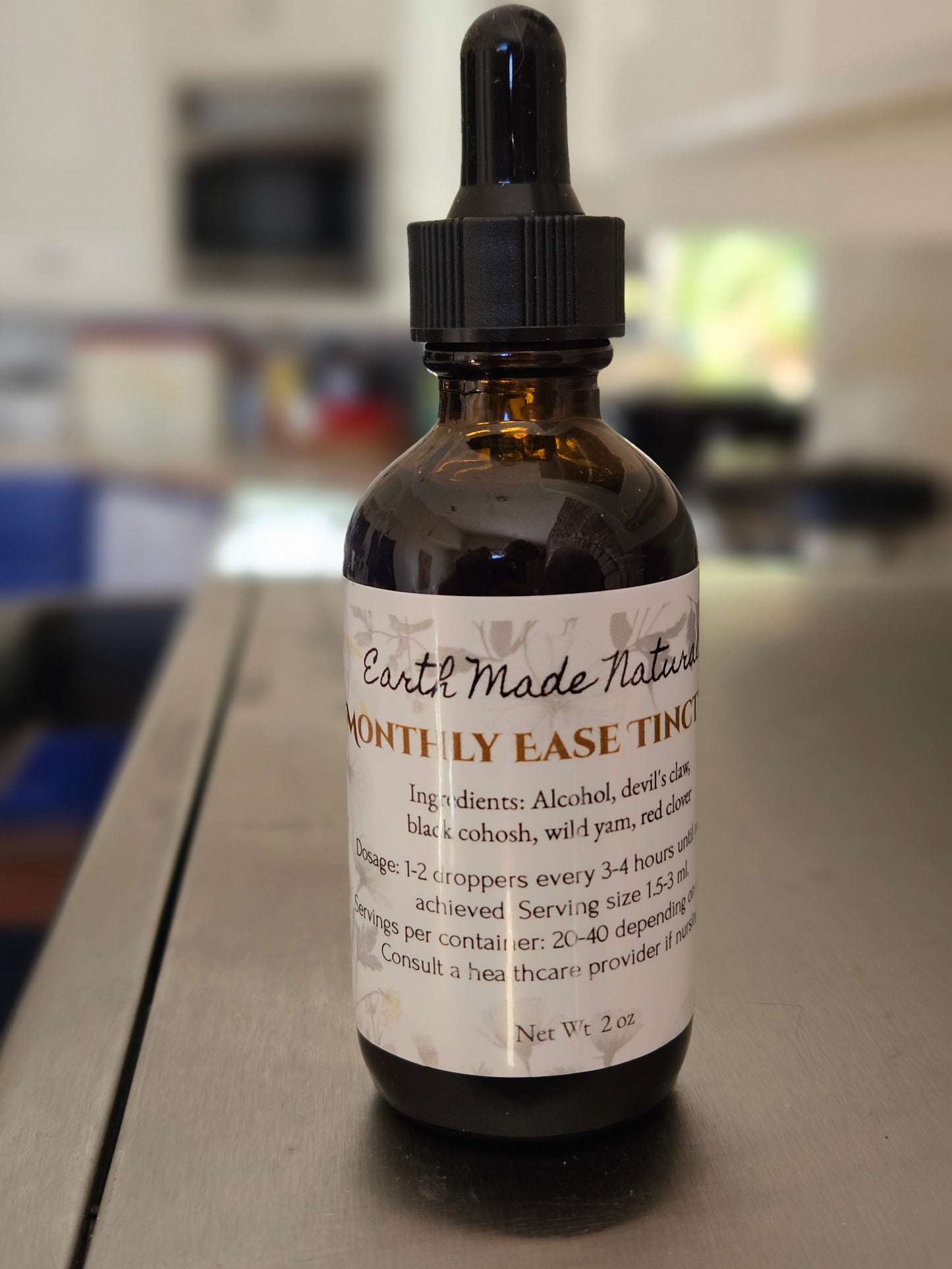 Bottle with dropper labeled 'monthly Ease Tincture' on a blurred background