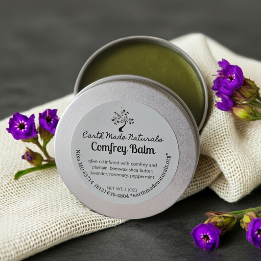 Earth Made Naturals Comfrey Balm tin with purple flowers on a dark background