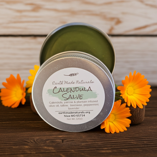 Open tin of Earth Made Naturals Calendula Salve with flowers on a wooden surface