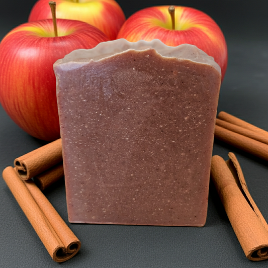 Bar of soap with apples and cinnamon sticks on a dark background