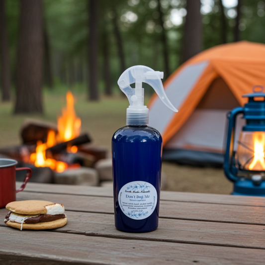 Blue spray bottle on a camping table with a s'more, campfire, and tent in the background.